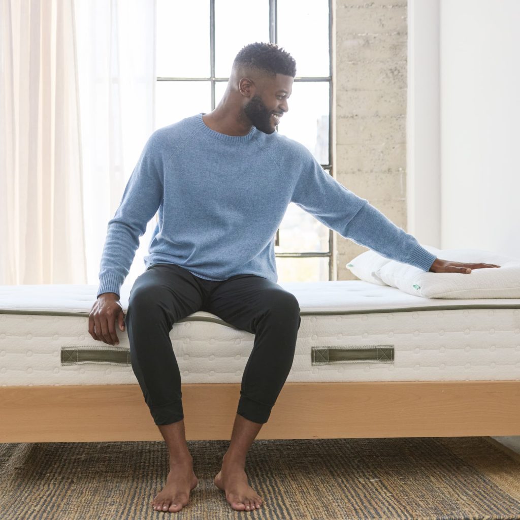 Man sitting on the edge of the Avocado Green Mattress