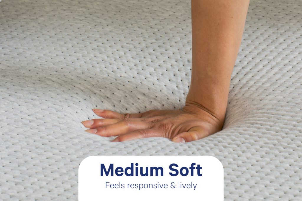 Hand pressing into the knit cover of the Casper Cloud One, labeled medium soft
