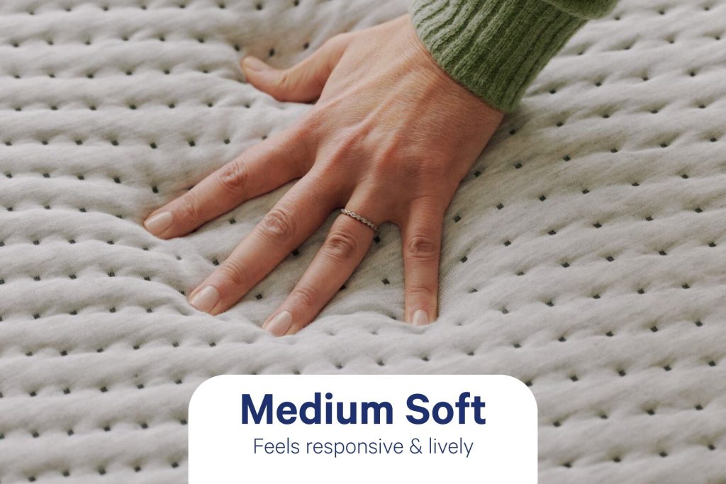 Hand pressing into the knit cover of the Casper Dream Max, labeled medium soft