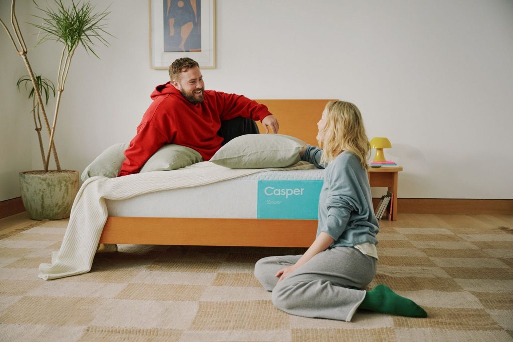 Couple relaxing on and beside the Casper Snow in a bedroom