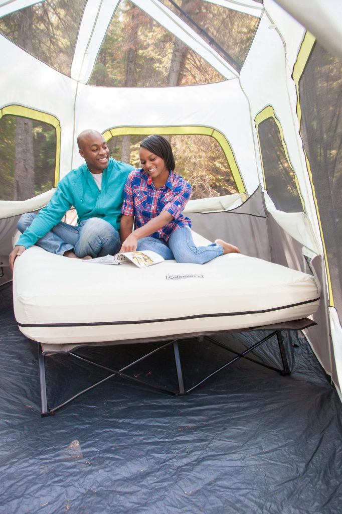 Couple sitting on a Coleman Queen Airbed Cot inside a tent