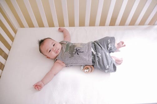 Baby lying on the Lullaby Earth Breathe Safe crib mattress