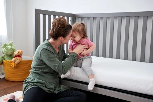 Parent and toddler next to the Lullaby Earth Breathe Safe in a crib