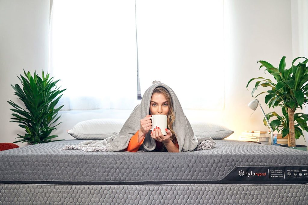 Woman with a mug sitting on the Layla Hybrid Mattress