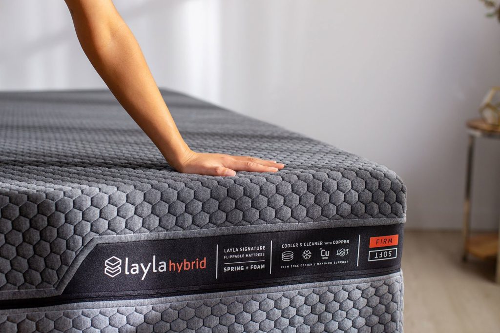 Hand pressing the hexagon cover of the Layla Hybrid Mattress