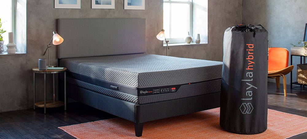 Layla Hybrid Mattress on a bed beside its rolled delivery bag
