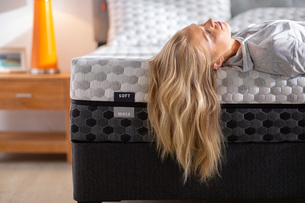 Woman lying back on the Layla Memory Foam Mattress with its soft and firm sides visible