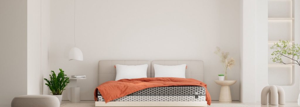 Layla Memory Foam Mattress made up with orange bedding in a wide bedroom