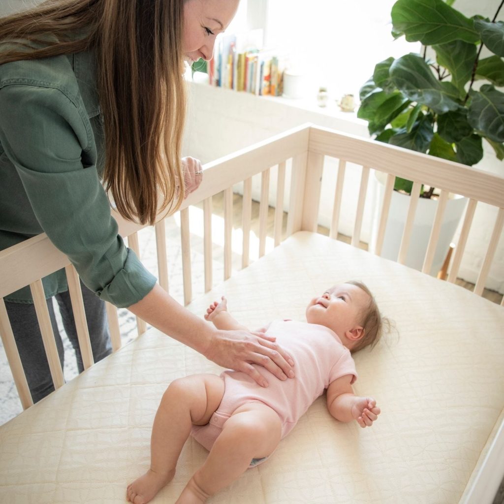 Parent with a baby on the Naturepedic Breathable Ultra crib mattress