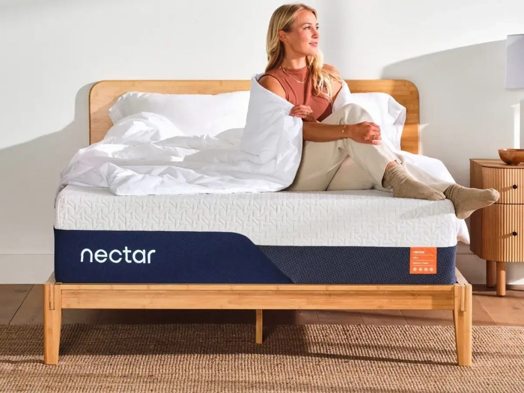 Woman sitting up on the Nectar Ultra Memory Foam mattress on a wooden bed frame