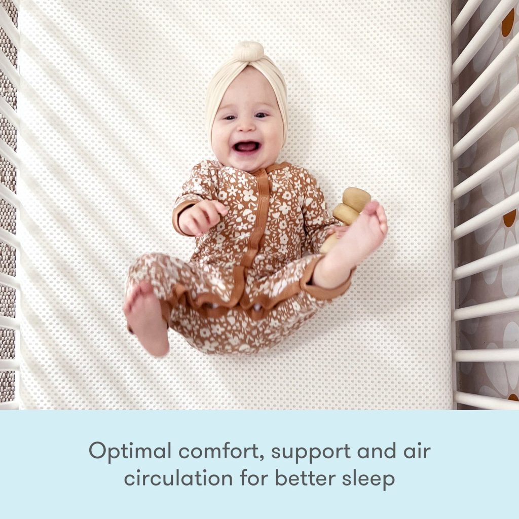 Baby lying on the eyelet cover of the Newton Essential crib mattress