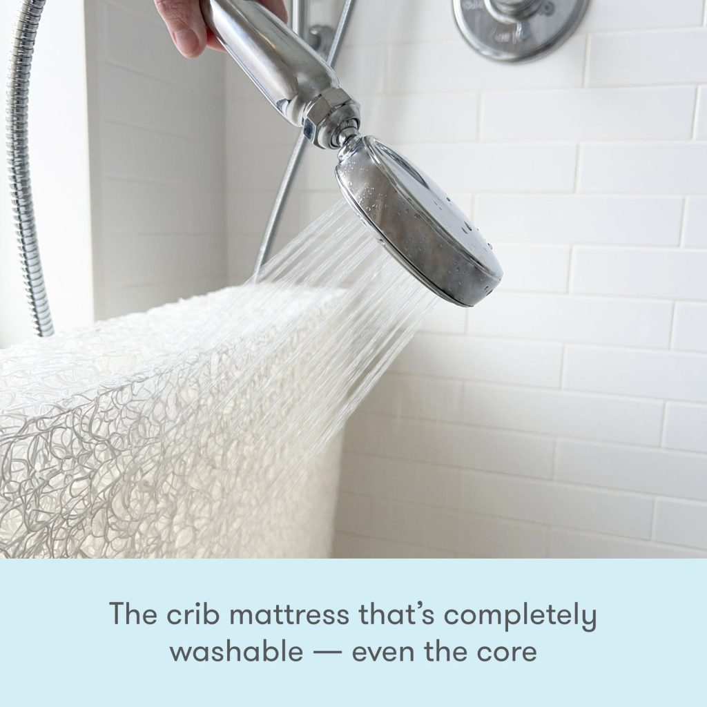 Newton Wovenaire crib mattress core being rinsed under a shower head