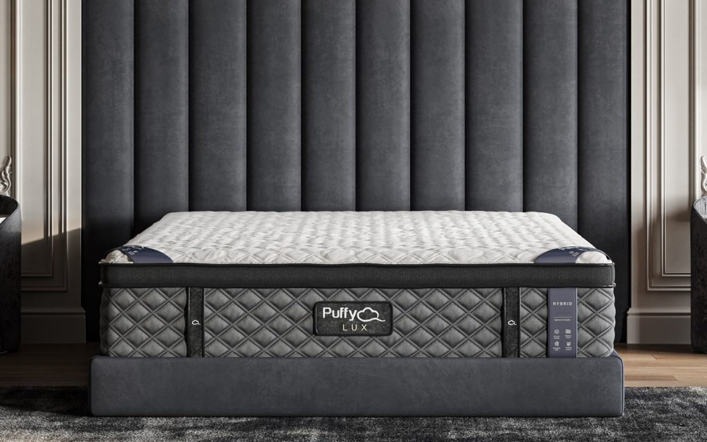 Puffy Lux Hybrid Mattress in a dark bedroom with a tall headboard