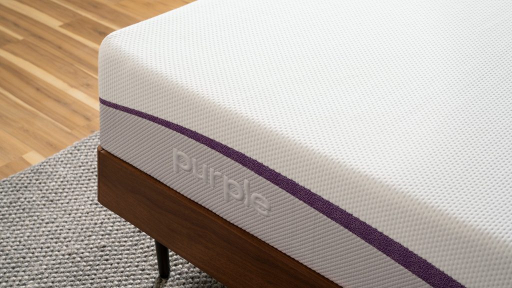 Corner of The Purple Mattress showing the white stretch cover and purple logo band