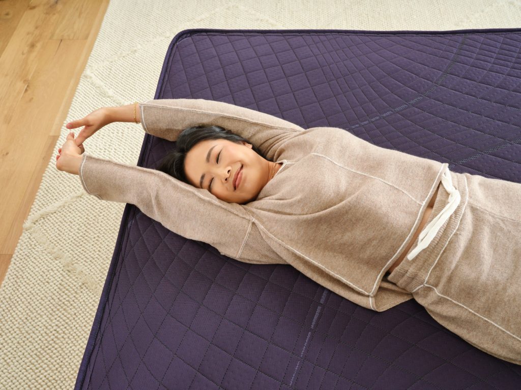Woman stretching on top of a Purple RejuvenatePlus mattress
