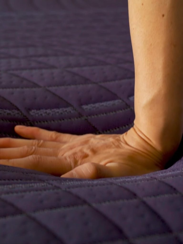 Hand pressing into the quilted DreamLayer top of the Purple RejuvenatePlus