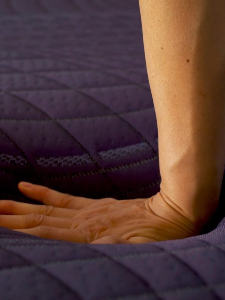 Hand pressing into the quilted top of the Purple RejuvenatePremier
