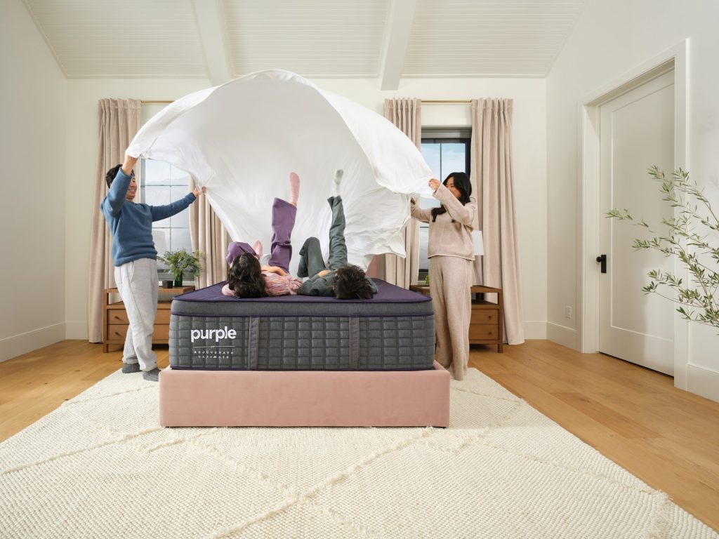 Family spreading a sheet over a Purple RejuvenateUltimate with a child lying on it