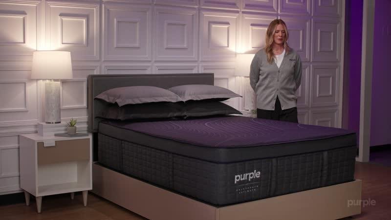 Purple staff member presenting a RejuvenateUltimate in a showroom bedroom
