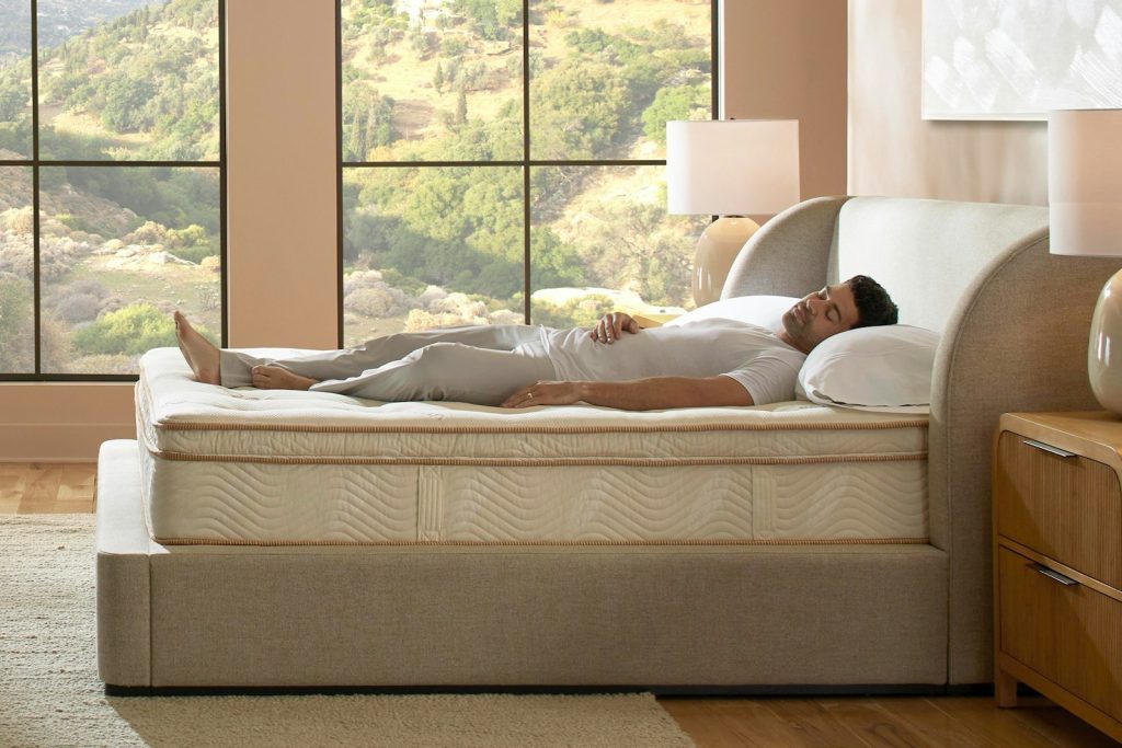Man lying on the Saatva Latex Hybrid next to a large window