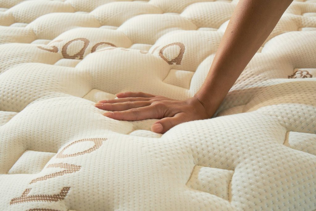 Hand pressing into the comfort layers of the Saatva Rx