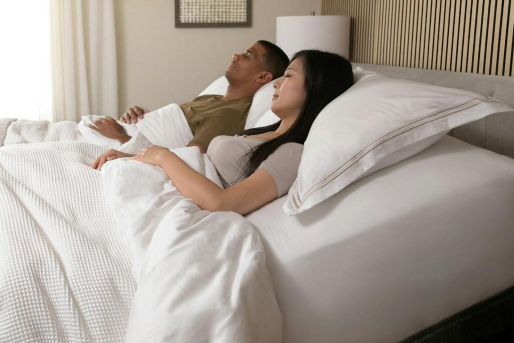 Couple resting on the Saatva Solaire with the head of the bed raised