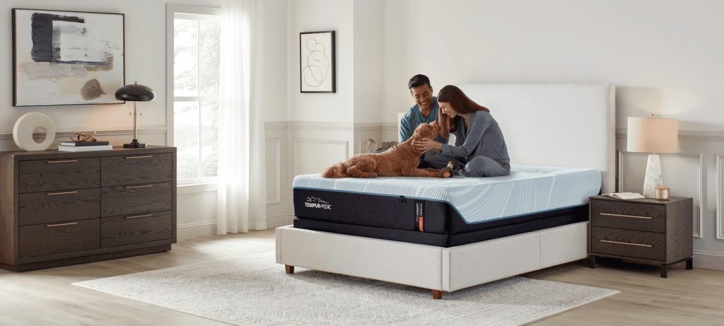 Couple and dog on a TEMPUR-ProAdapt mattress in a white bedroom